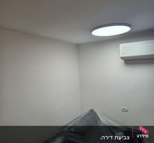 חדר עם קירות צבועים ורהיטים מכוסים בניילון.